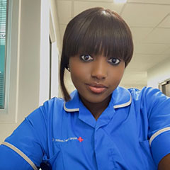 A nurse in blue uniform looks at the camera