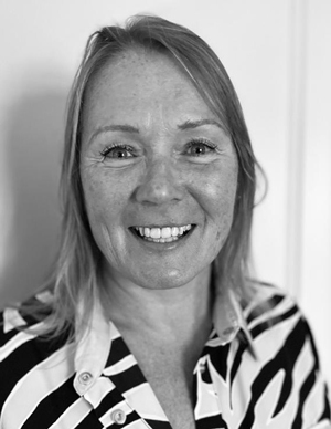 A head and shoulders portrait of a smiling woman in black and white