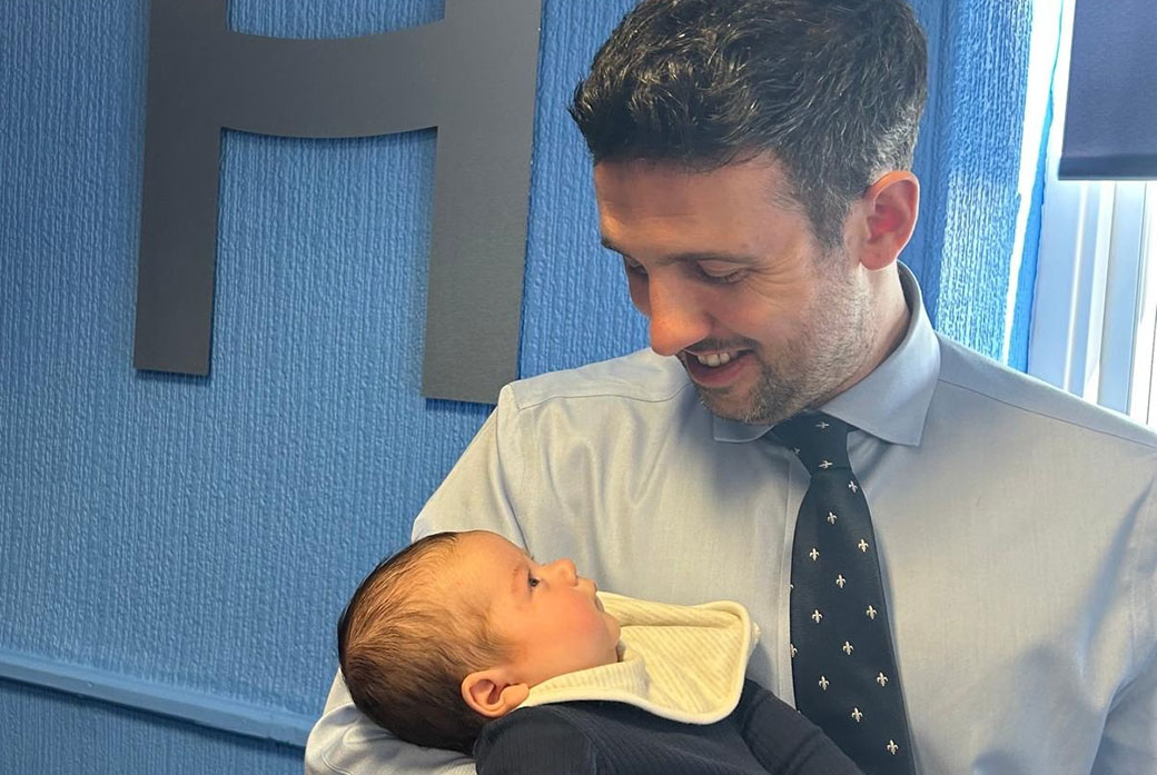 A man looks at the baby he is holding in his arms
