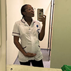 A pregnant nurse takes a picture in the mirror