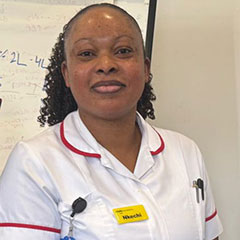 A nurse in a white uniform looks at the camera