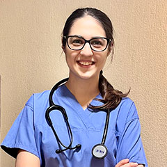 A nurse in blue uniform looks at the camera