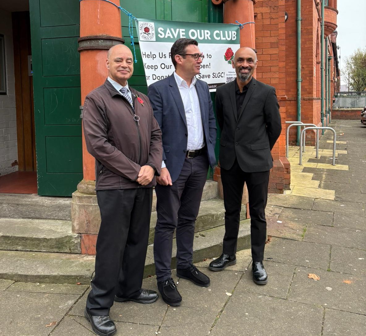 Three men in suits talking to each other, one is Manchester Mayor