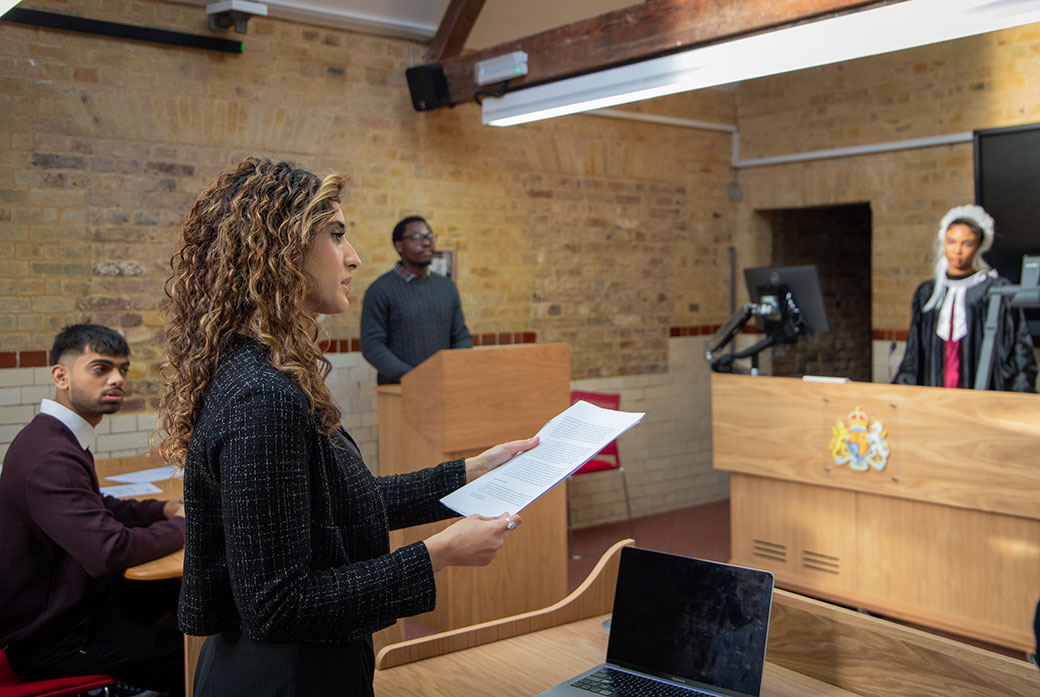 A barrister holds paper in a mock student courtroom