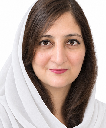 A woman wearing a white headscarf looks at the camera