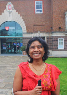 Deepika Nallathambi middlesex uni alumni wearing a red top in front of a red brick building
