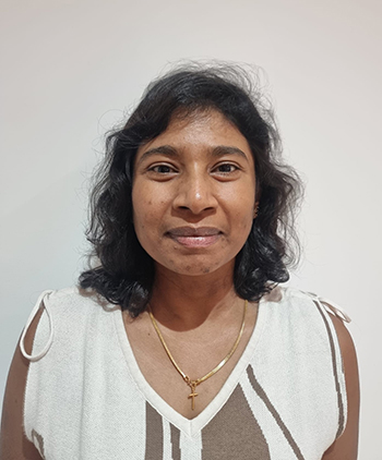 A woman smiles at the camera against a beige background