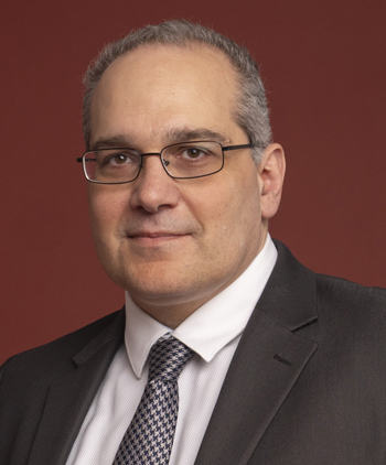 A man in a jacket and tie smiles at the camera