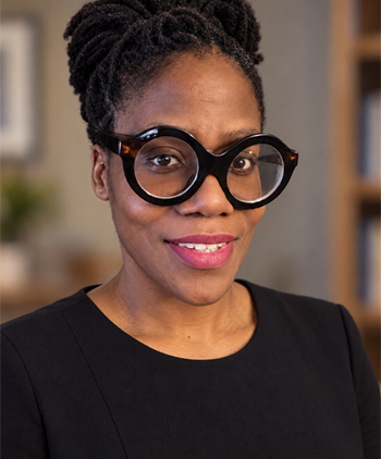 A woman with large glasses smiles at the camera