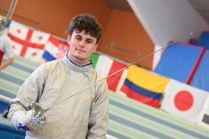 Olympios Gougoulias in fencing attire holding his foil in the arena.