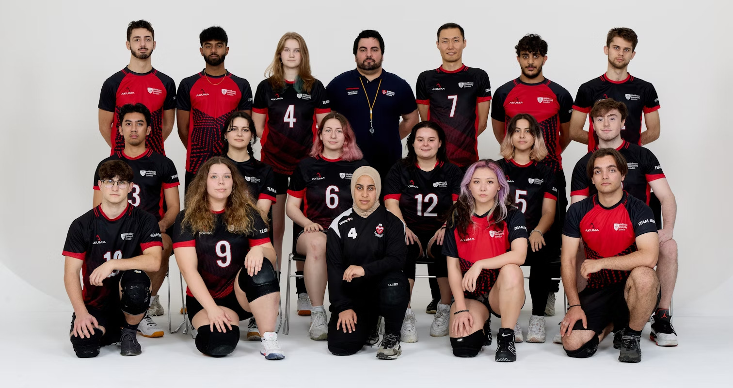 A group of individuals in red and black uniforms stand together, looking directly at the camera, ready for a team photograph.