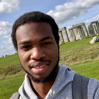 A young man named Euan standing in front of Stonehenge, looking up at the ancient stone monument.