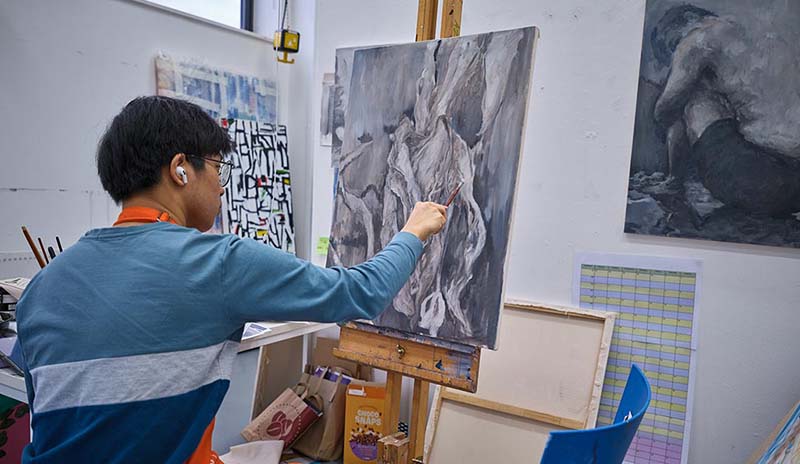 Art student painting on canvas in art studio