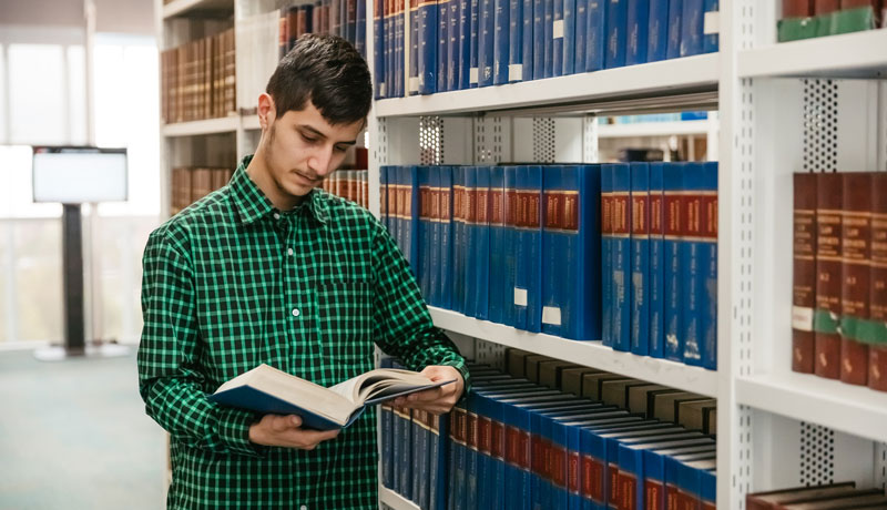 Male law student reading book in library