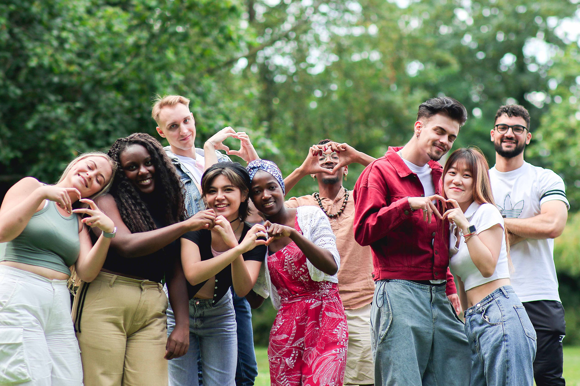 large group of happy students make heart shapes with their hands