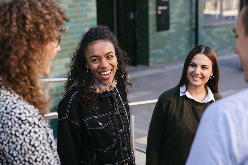 Three young women engaged in conversation in front of a building.