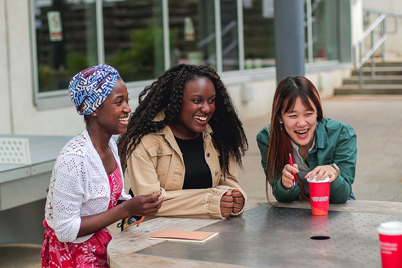 Three women enjoying coffee together at a table.